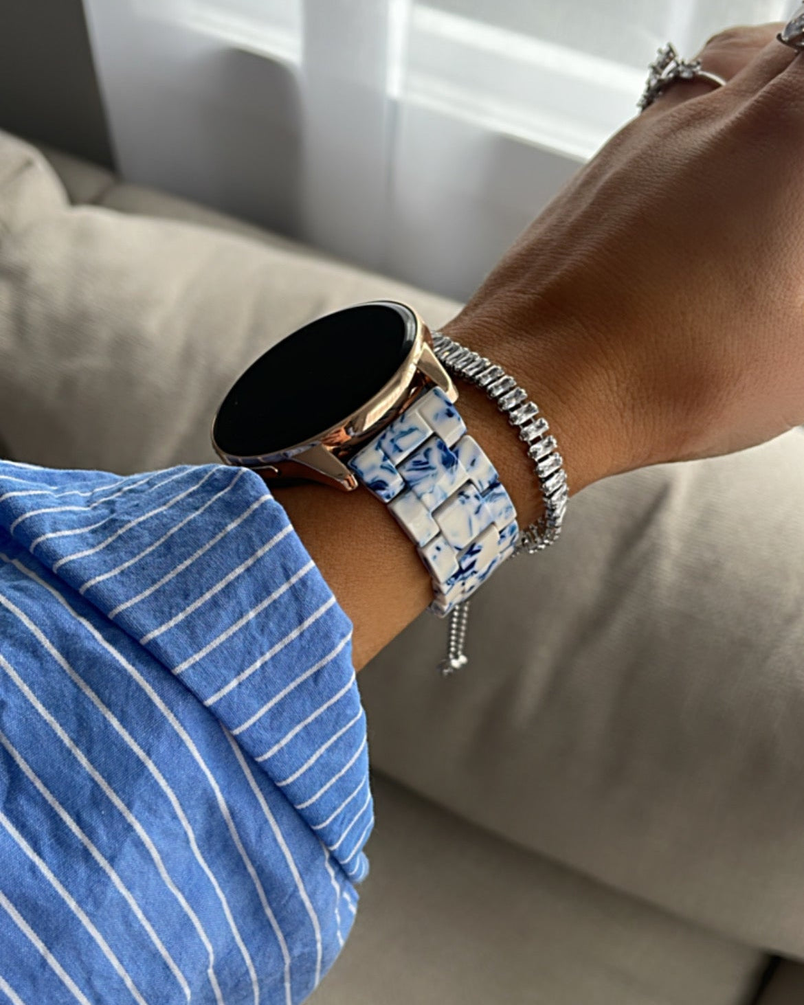 Person wearing a smartwatch and bracelet on a neutral background