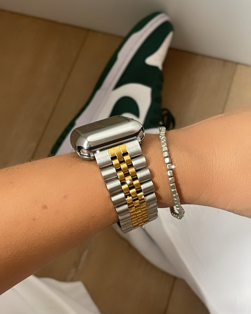 Close-up of a wrist wearing a silver and gold bracelet with a blurred background.