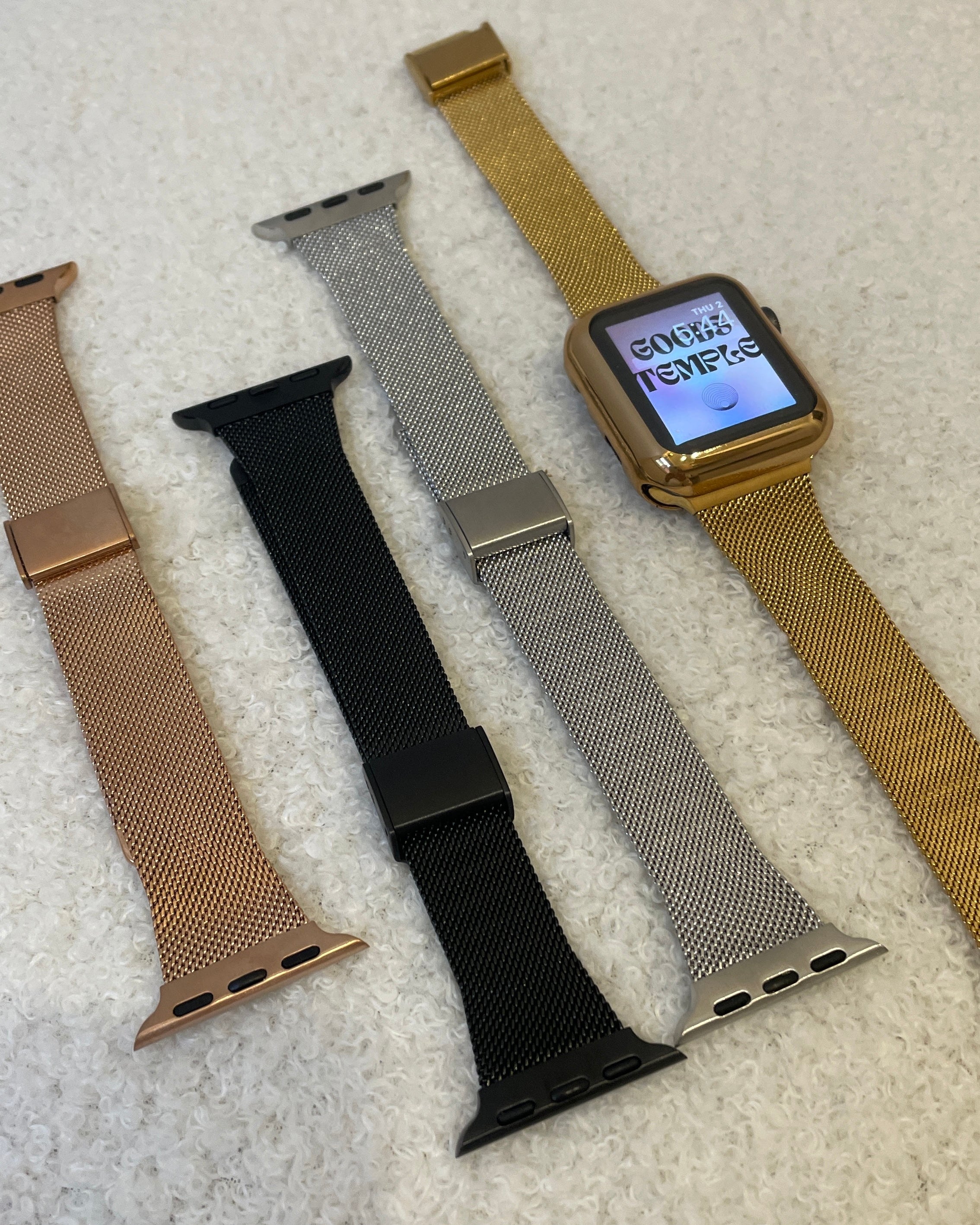 Smartwatch with four different metal watch bands on a textured surface