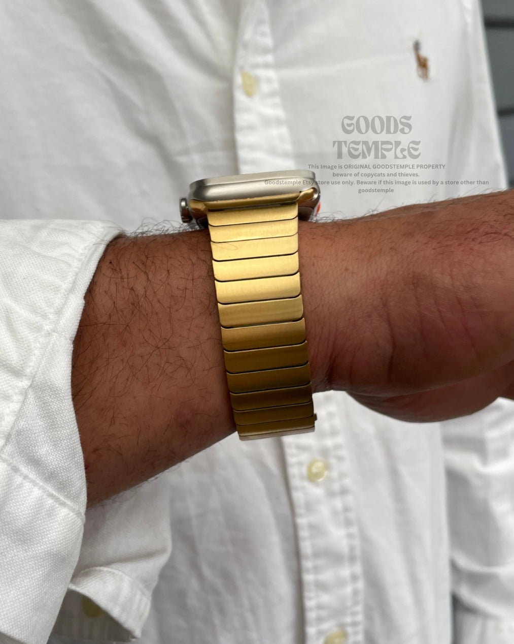 Gold watch on a wrist with a white shirt background