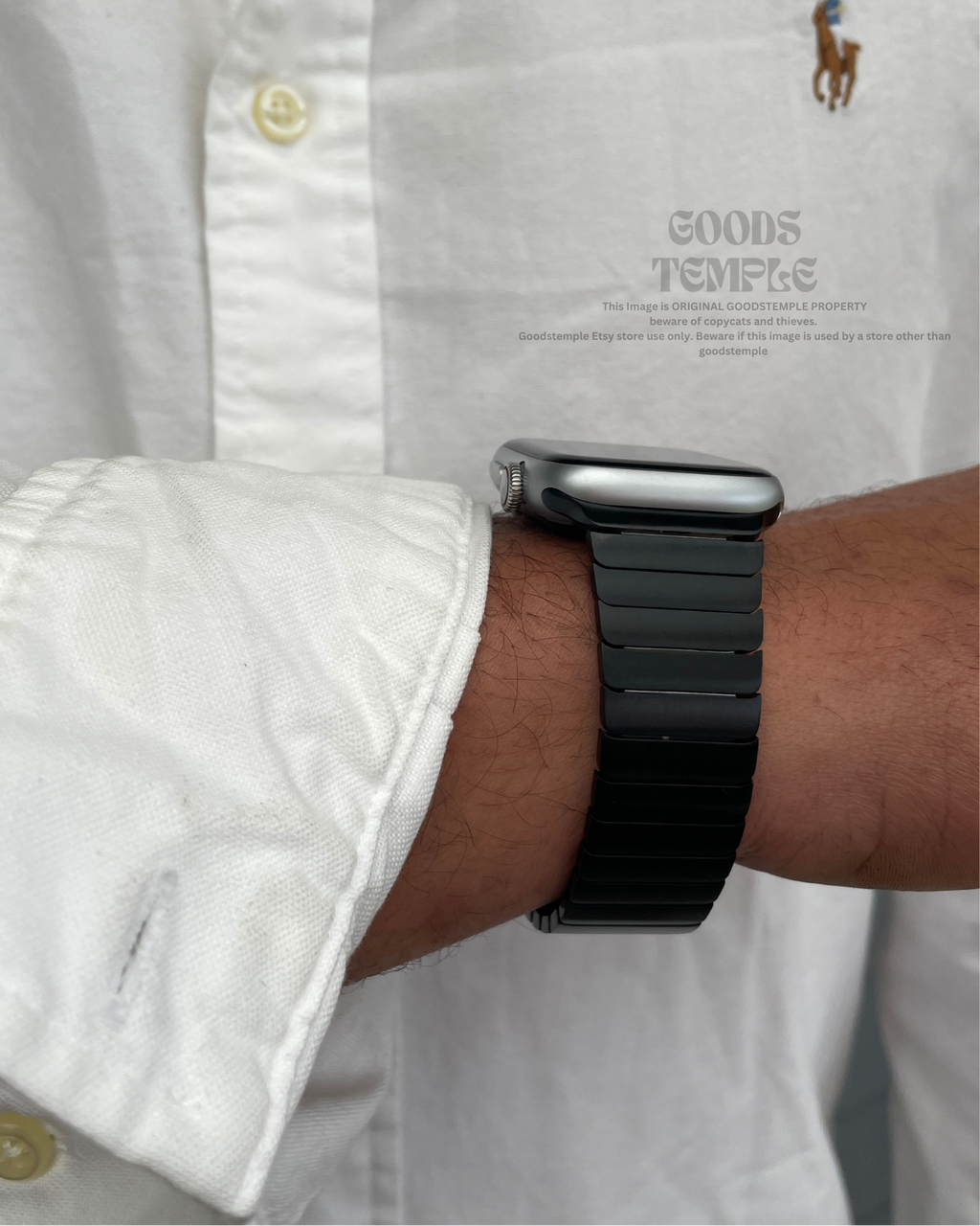 Person wearing a black smartwatch on a white shirt with a visible brand logo.