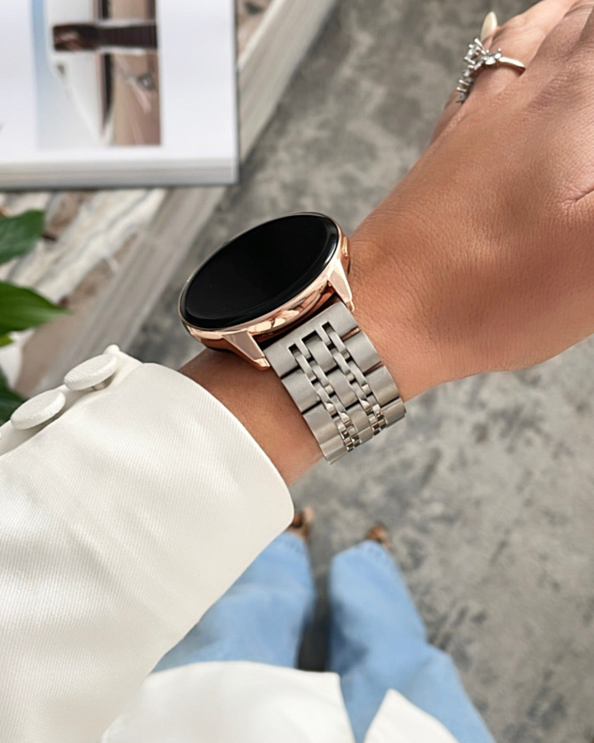 Close-up of a wrist wearing a smartwatch with a metallic band, blurred background