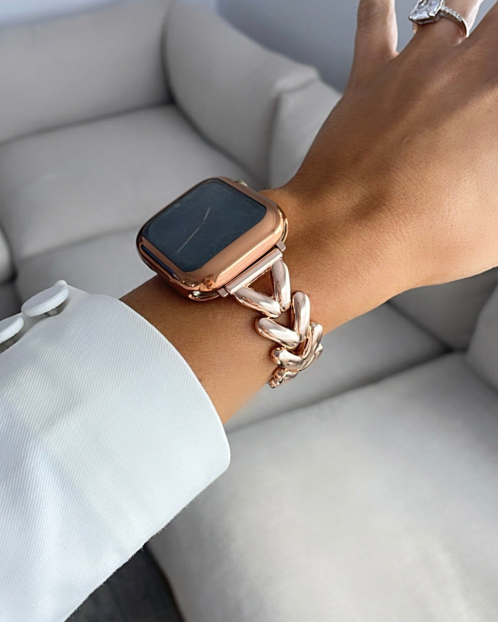 Smartwatch with a rose gold band on a wrist, with a blurred background