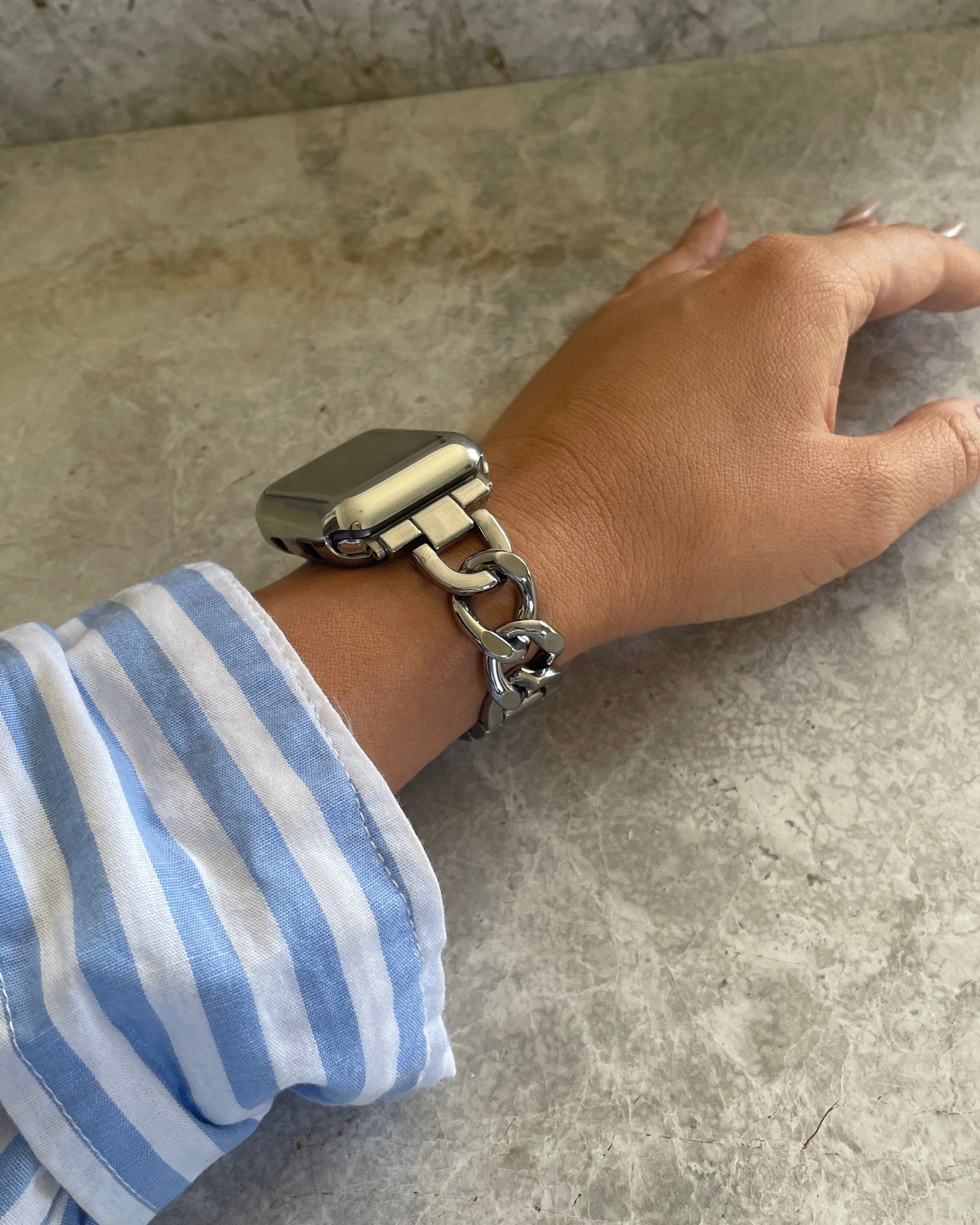 Hand wearing a silver bracelet on a concrete surface