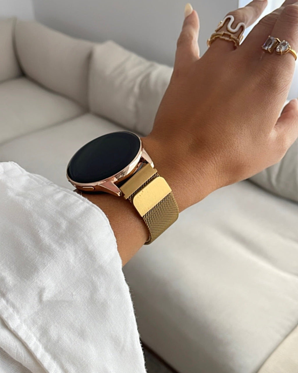 Hand wearing a gold smartwatch with a blurred background