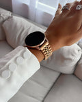Hand wearing a gold watch on a light-colored sofa with a blurred background
