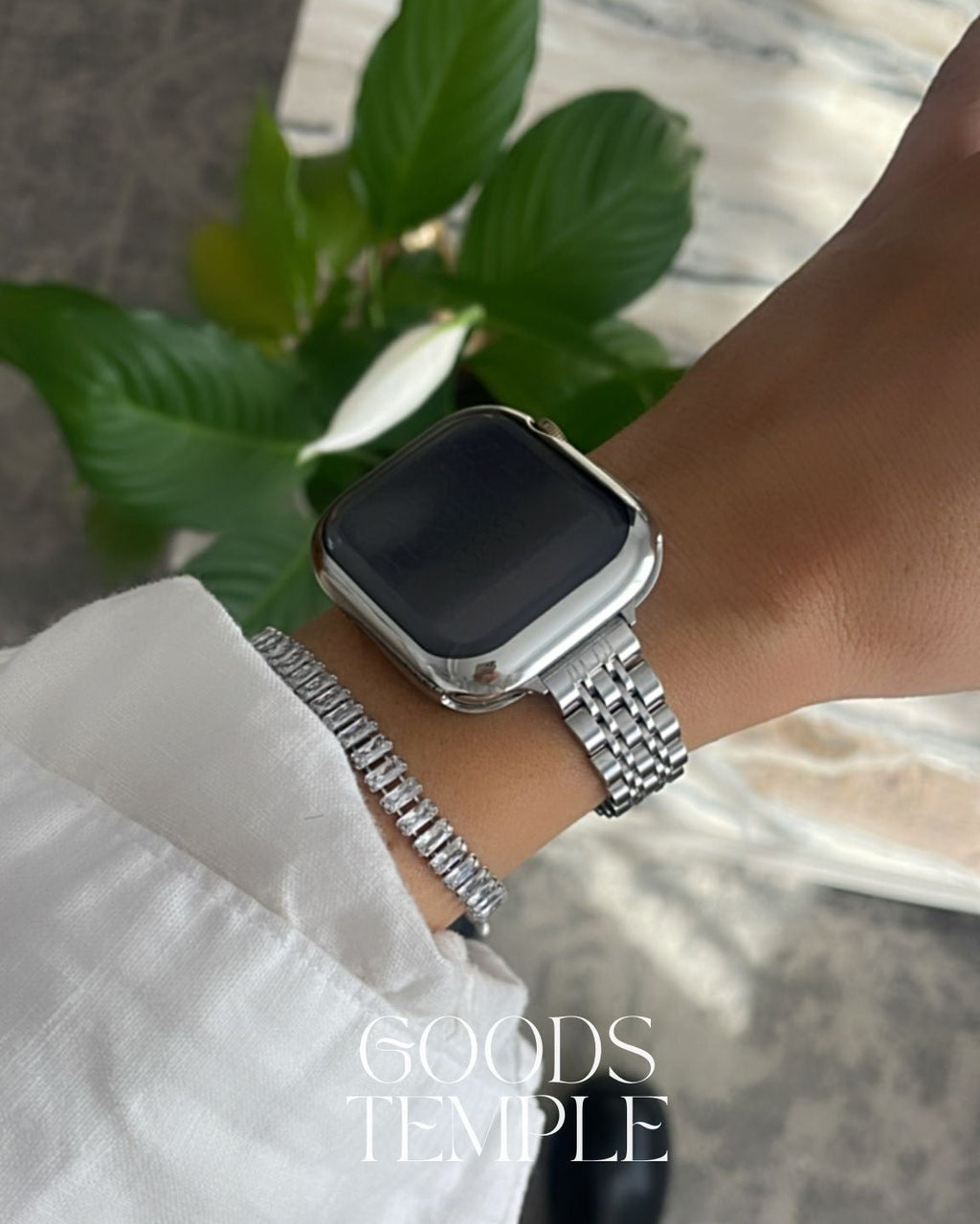 Smartwatch on a wrist with a blurred background and 'GOODS TEMPLE' branding.