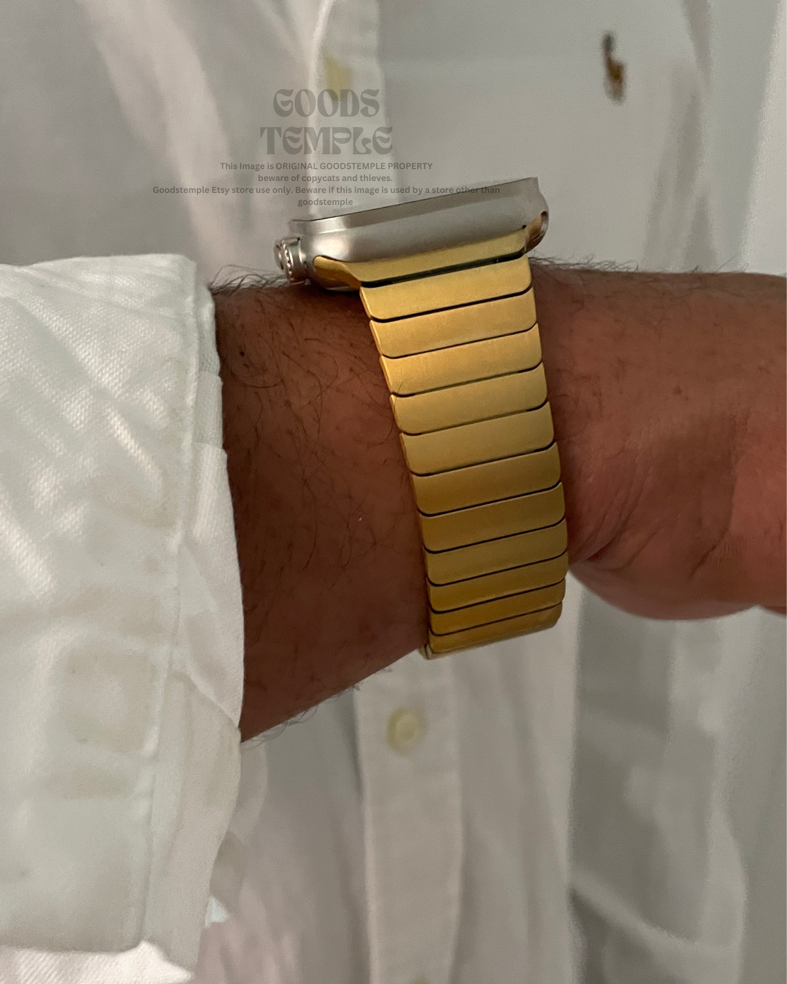 Gold watch band on a wrist with a white shirt background