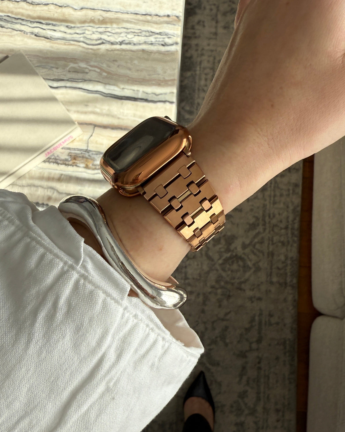 Gold watch on a wrist with a neutral background