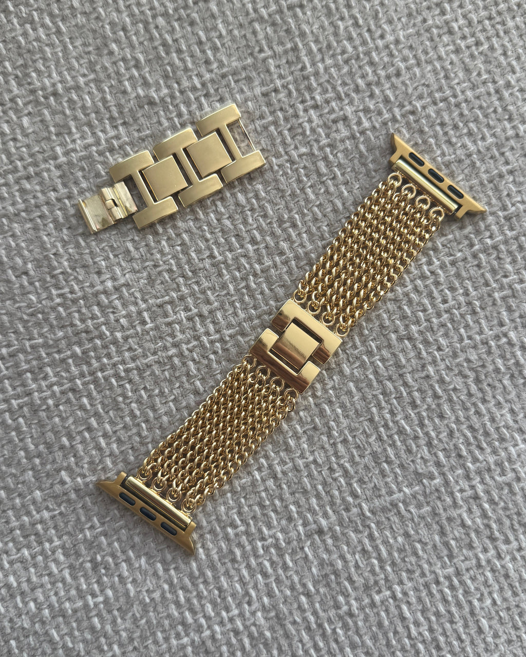 Gold watch strap and clasp on a gray textured background