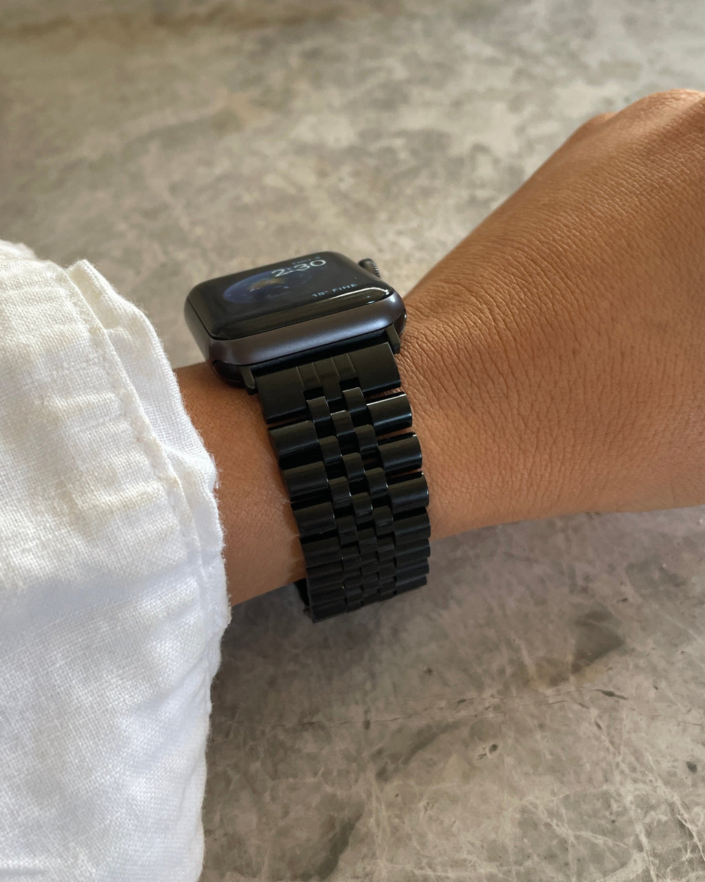 Person wearing a black smartwatch on a marble surface