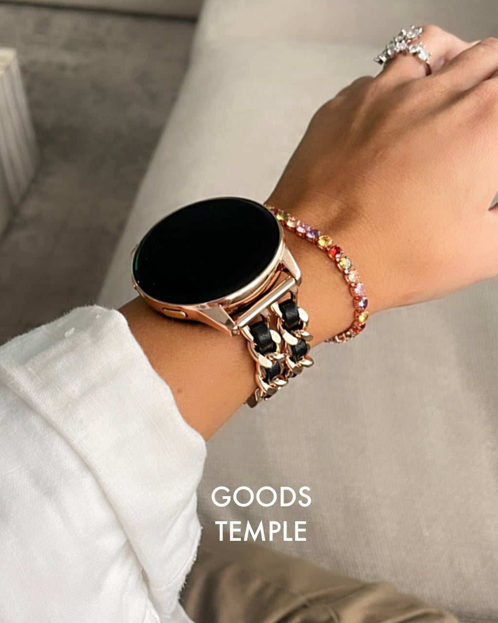 Hand wearing a smartwatch and bracelets with 'GOODS TEMPLE' branding.