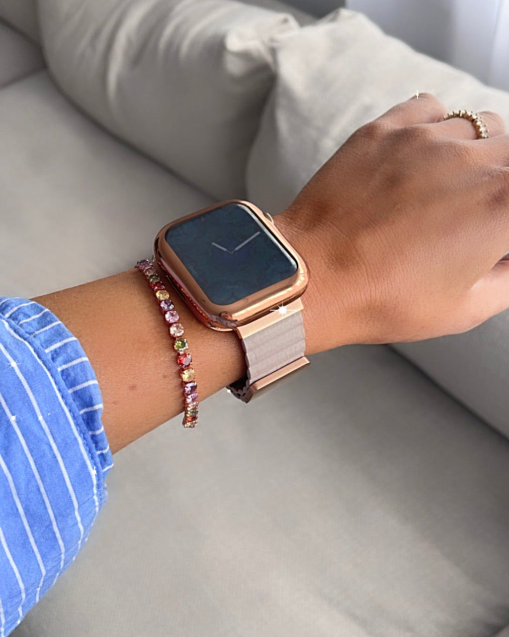 Person wearing a smartwatch and bracelet on a gray couch