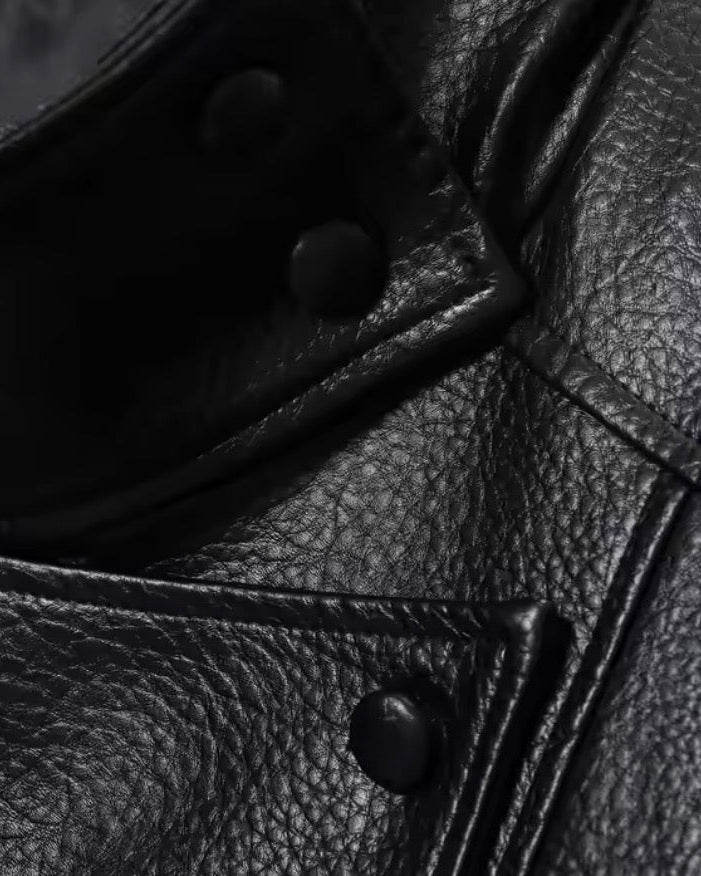 Close-up of a black leather jacket with buttons on a white background