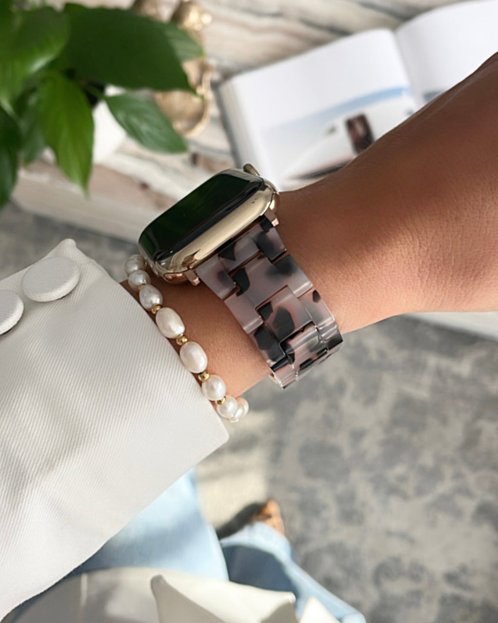 Person wearing a smartwatch and bracelet with a blurred background