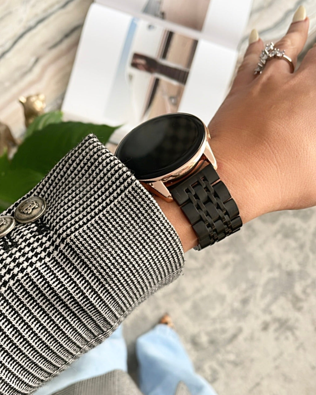 Person wearing a black smartwatch on a blurred outdoor background