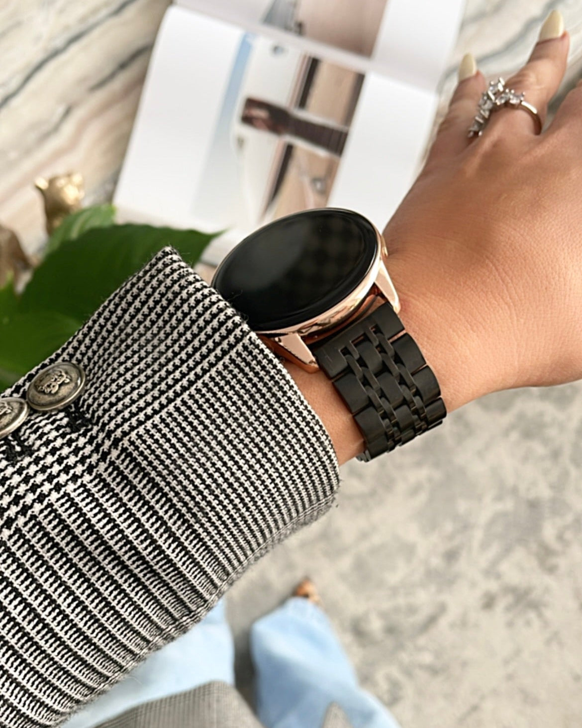 Person wearing a black smartwatch on a blurred outdoor background
