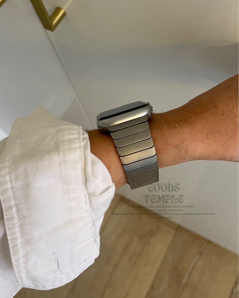 Person wearing a metallic watch on a blurred indoor background