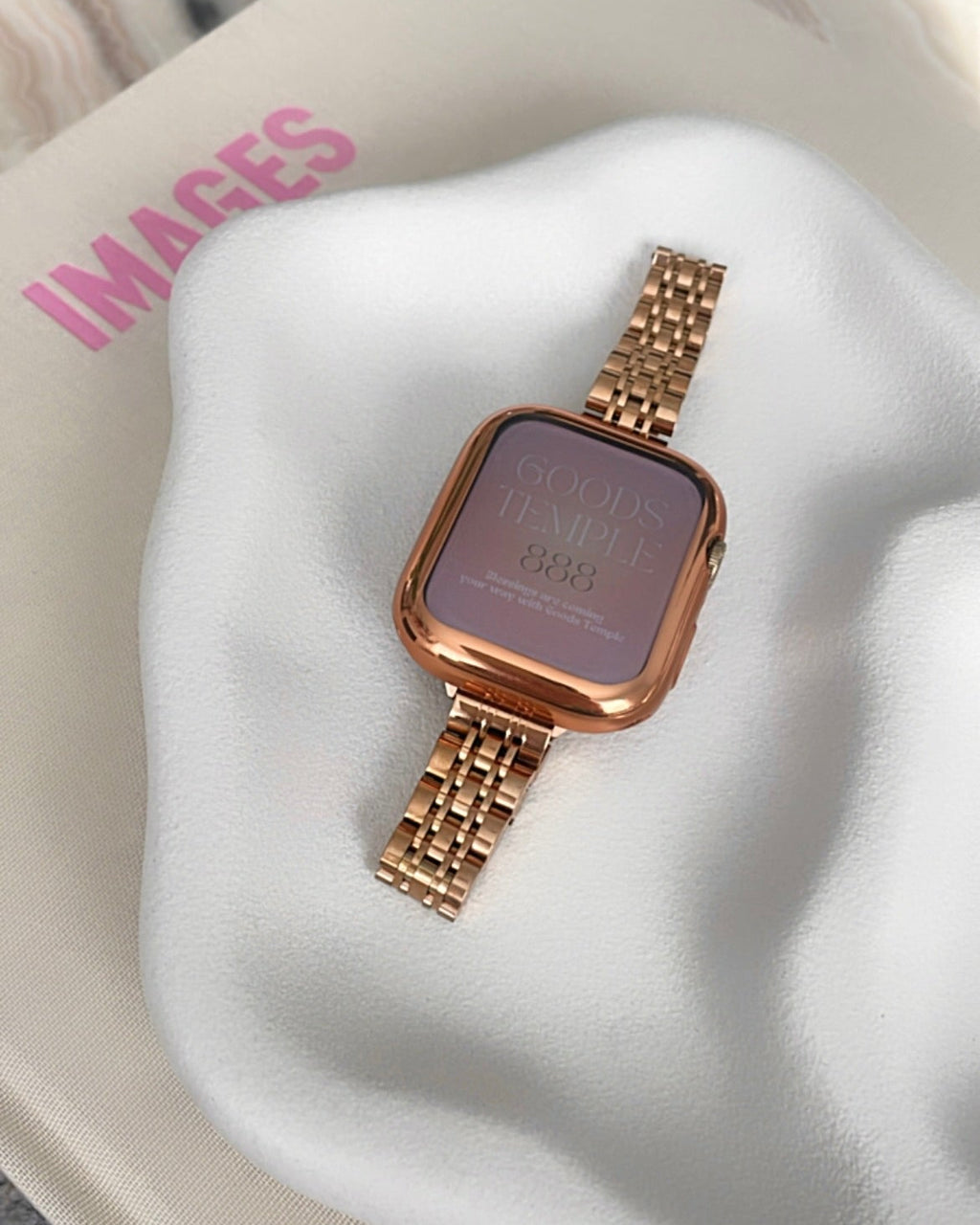 Rose gold watch on a white cushion with 'IMAGES' branding.