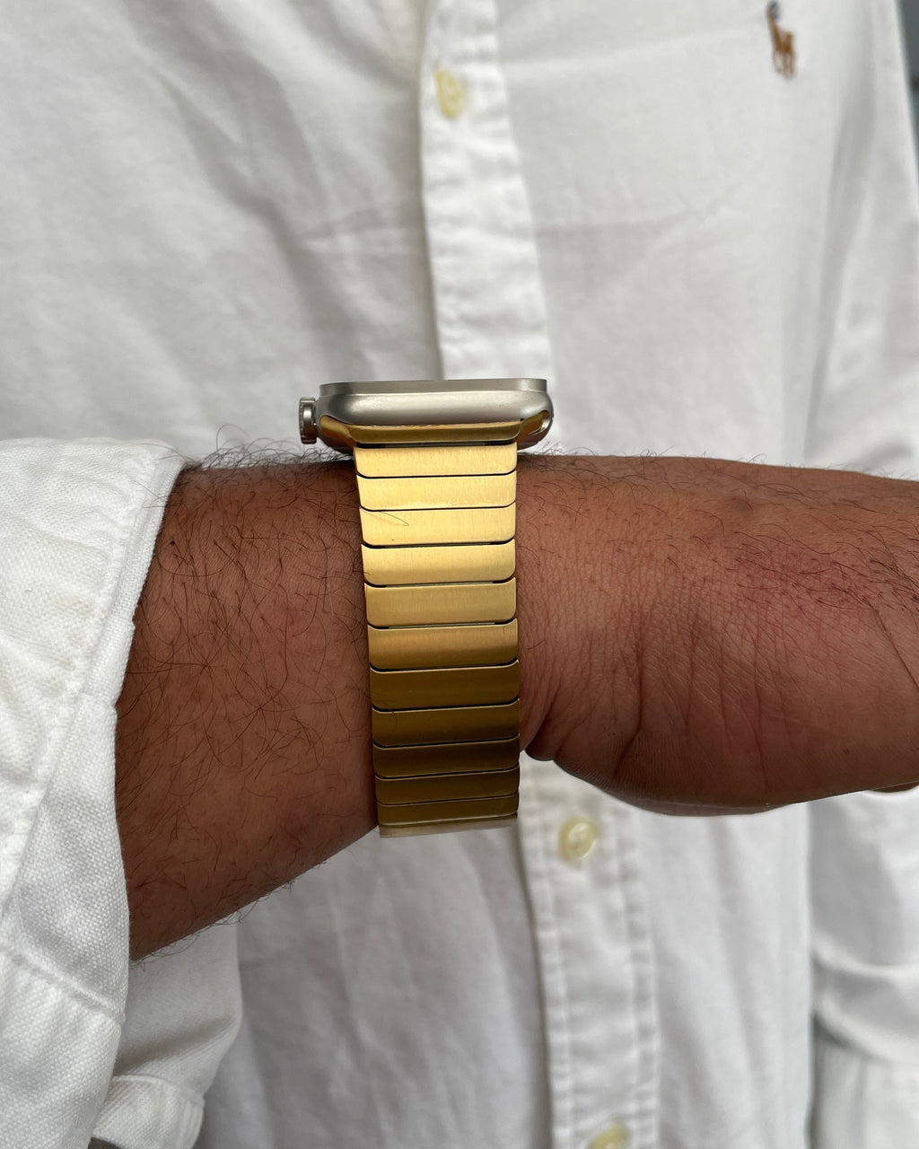 Gold watch on a wrist with a white shirt background