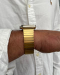 Gold watch on a wrist with a white shirt background