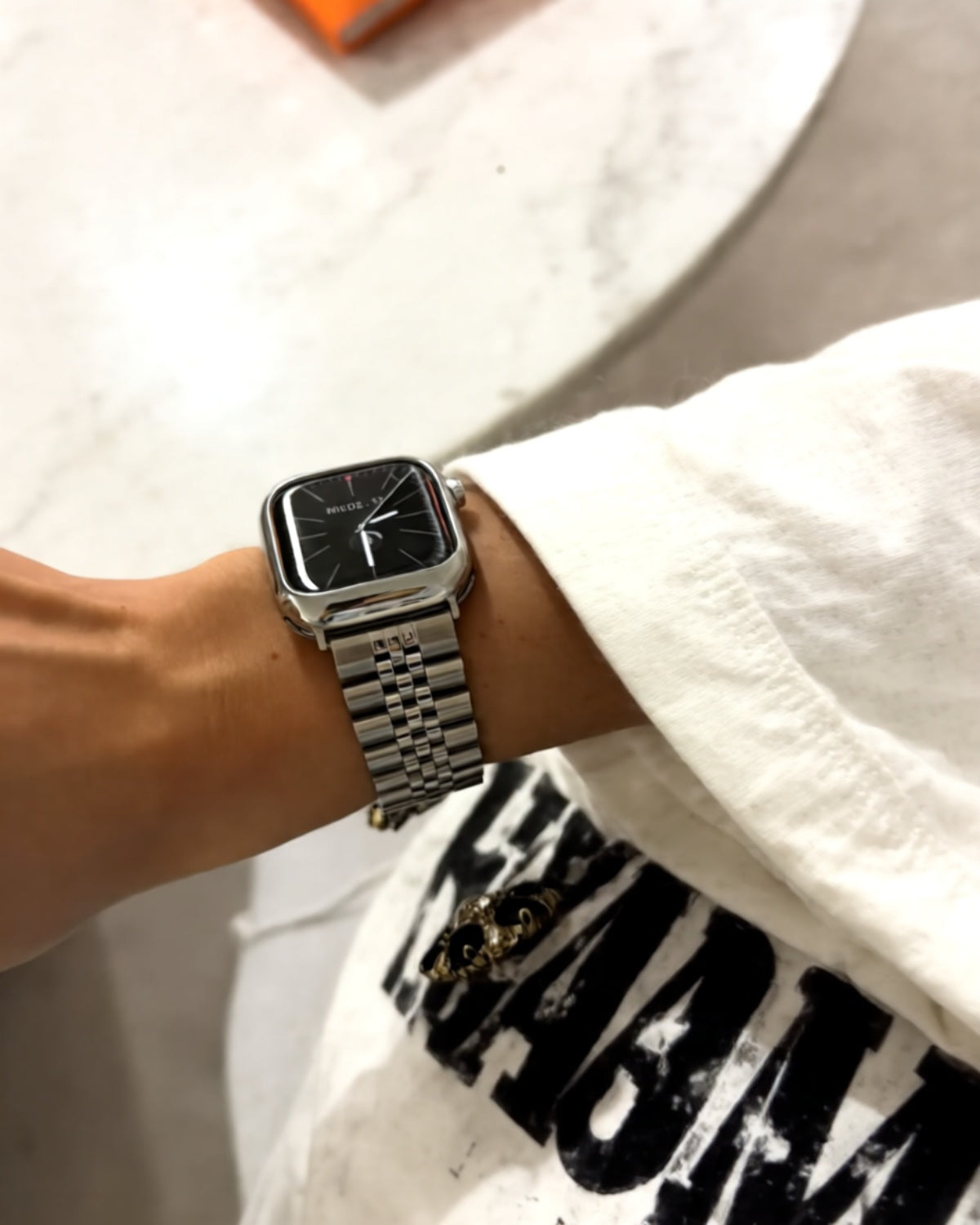 Person wearing a silver watch on a white background