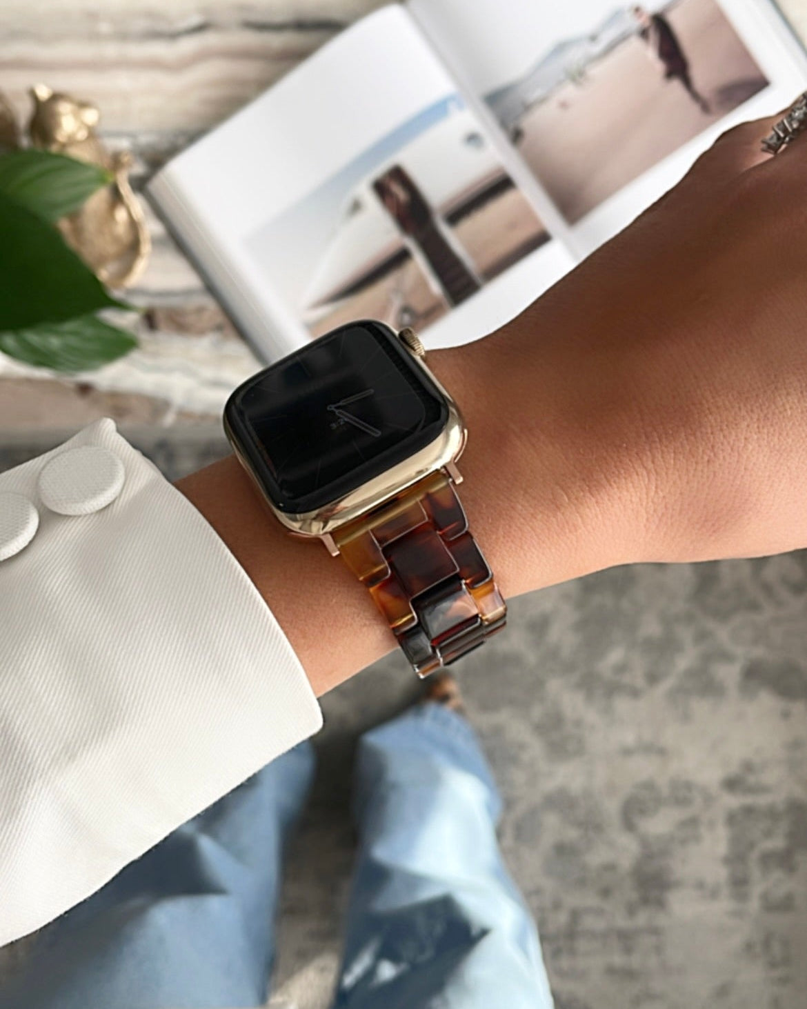Smartwatch with a brown leather strap on a wrist, with a magazine in the background.