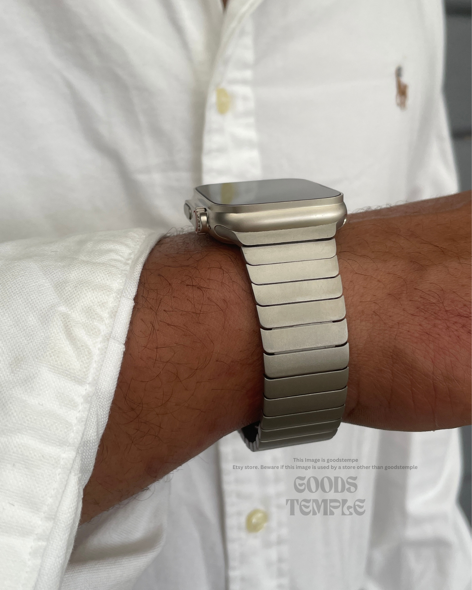 Silver watch on a wrist with a white shirt in the background
