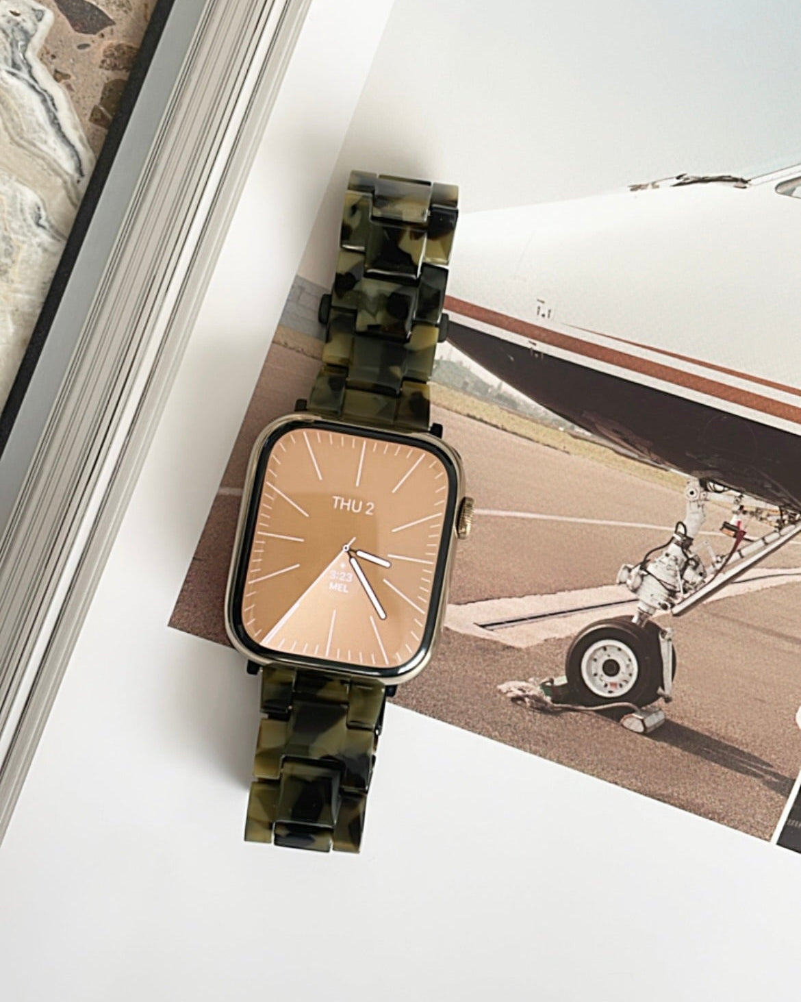 Watch with a brown strap on a surface with a vintage airplane photo in the background