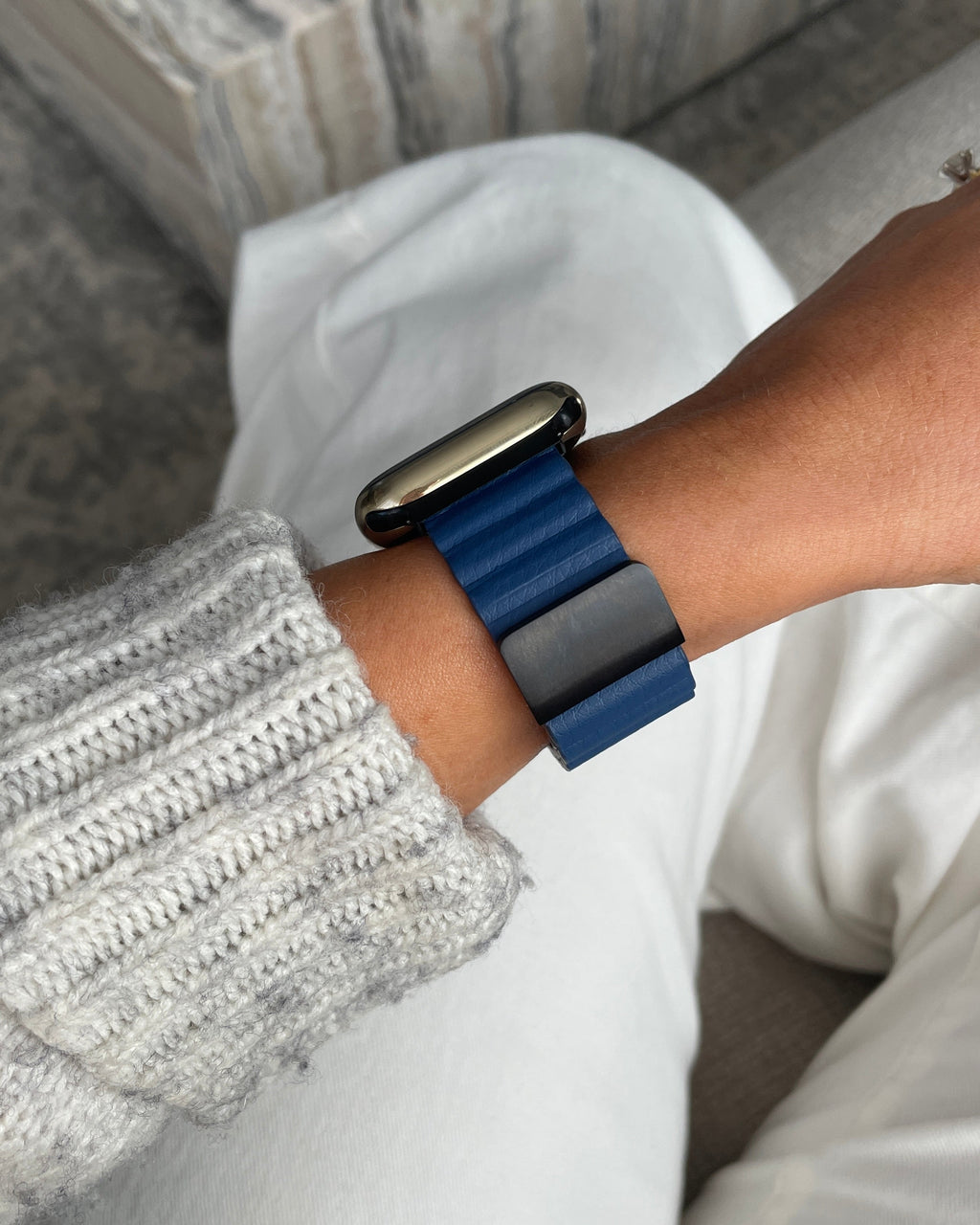 Person wearing a smartwatch with a blue band on a neutral background
