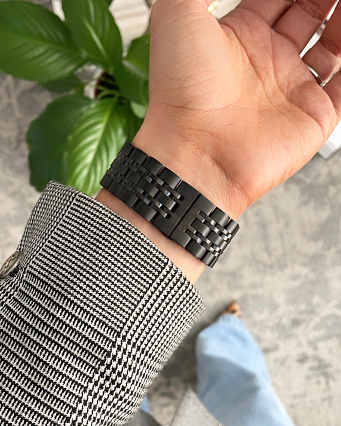 Hand wearing a black woven bracelet with a blurred background