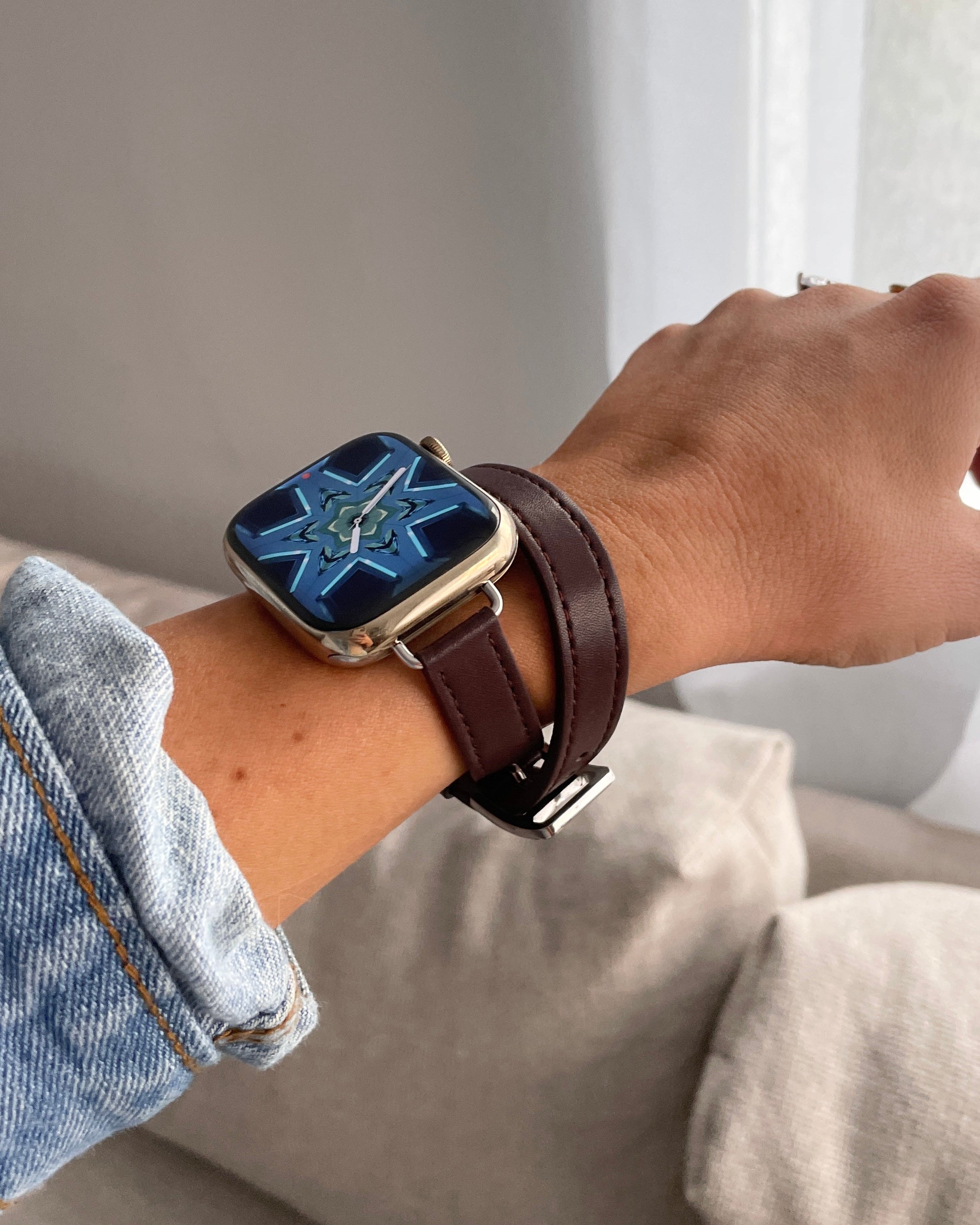 Smartwatch with a brown leather strap on a wrist, with a neutral background