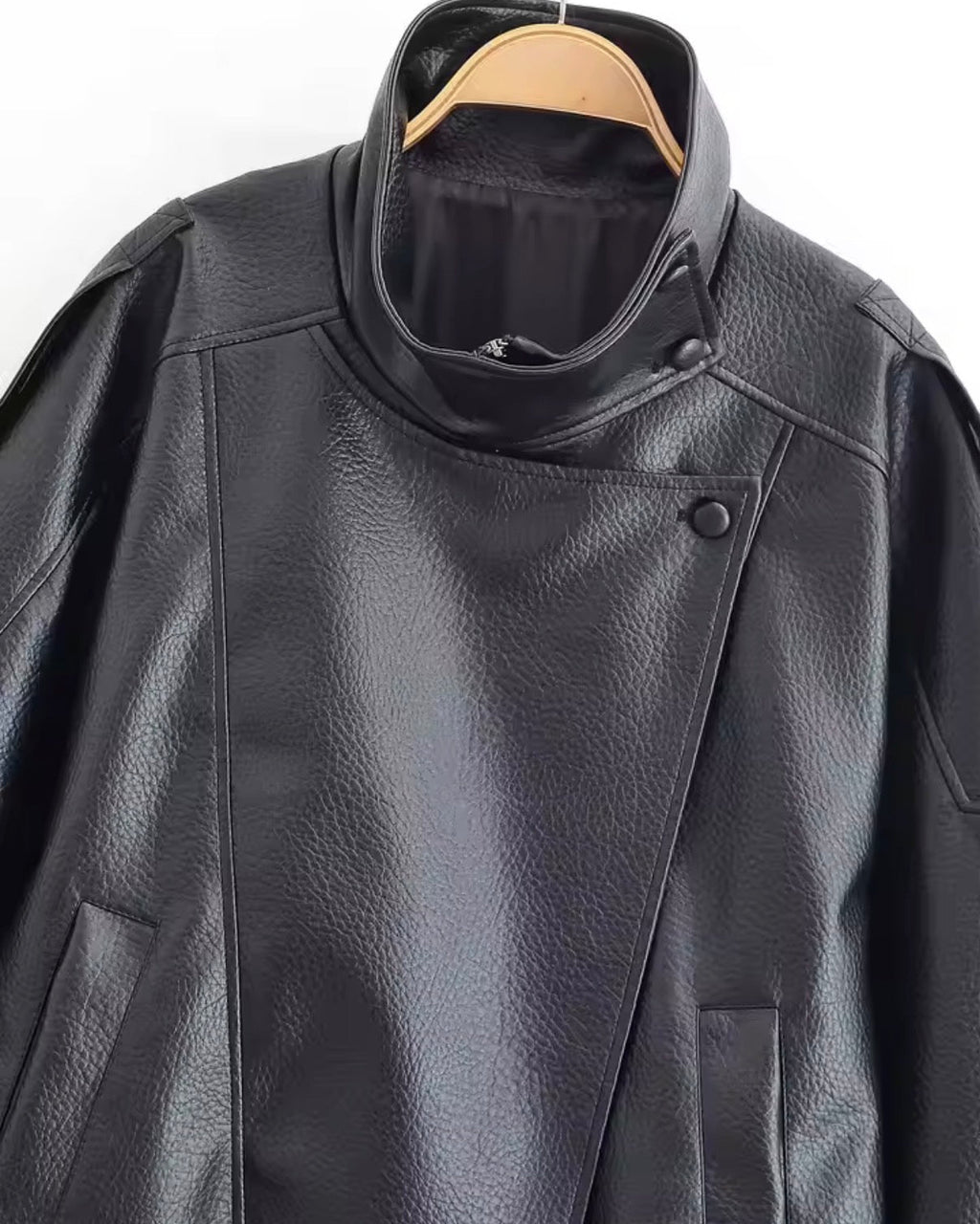 Close-up of a black leather jacket with a textured finish on a white background