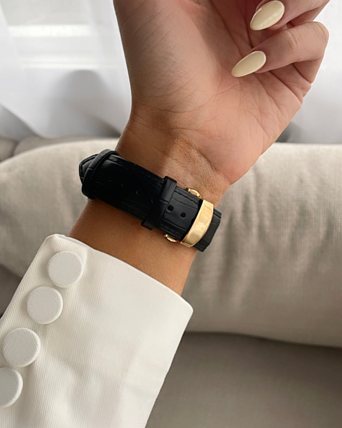 Hand wearing a black watch with gold accent on a white background