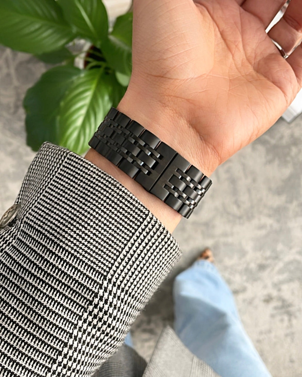 Hand wearing a black woven bracelet with a blurred background