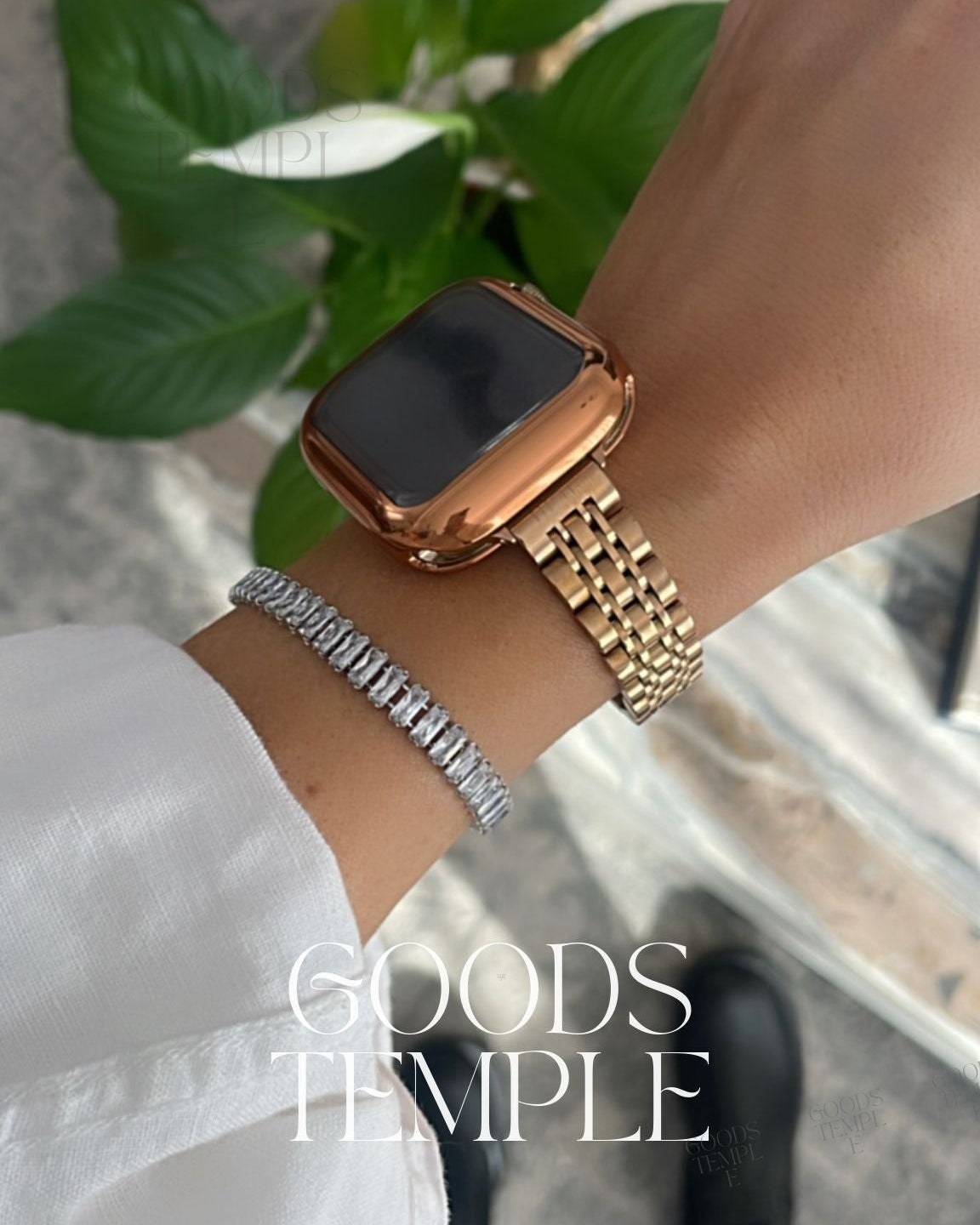 Gold smartwatch on a wrist with a blurred background and 'GOODS TEMPLE' branding.