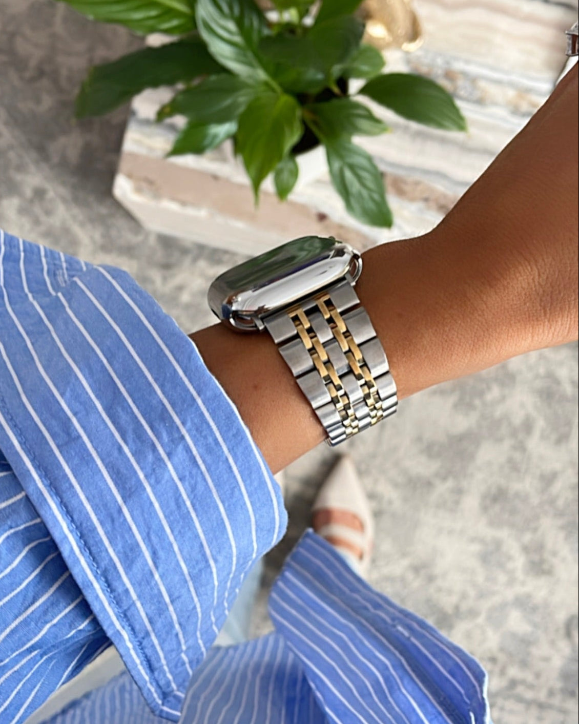 Person wearing a silver watch with a gold band on a blurred background