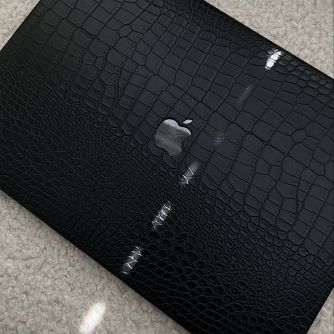 Black crocodile-patterned wallet with Apple logo on a gray surface