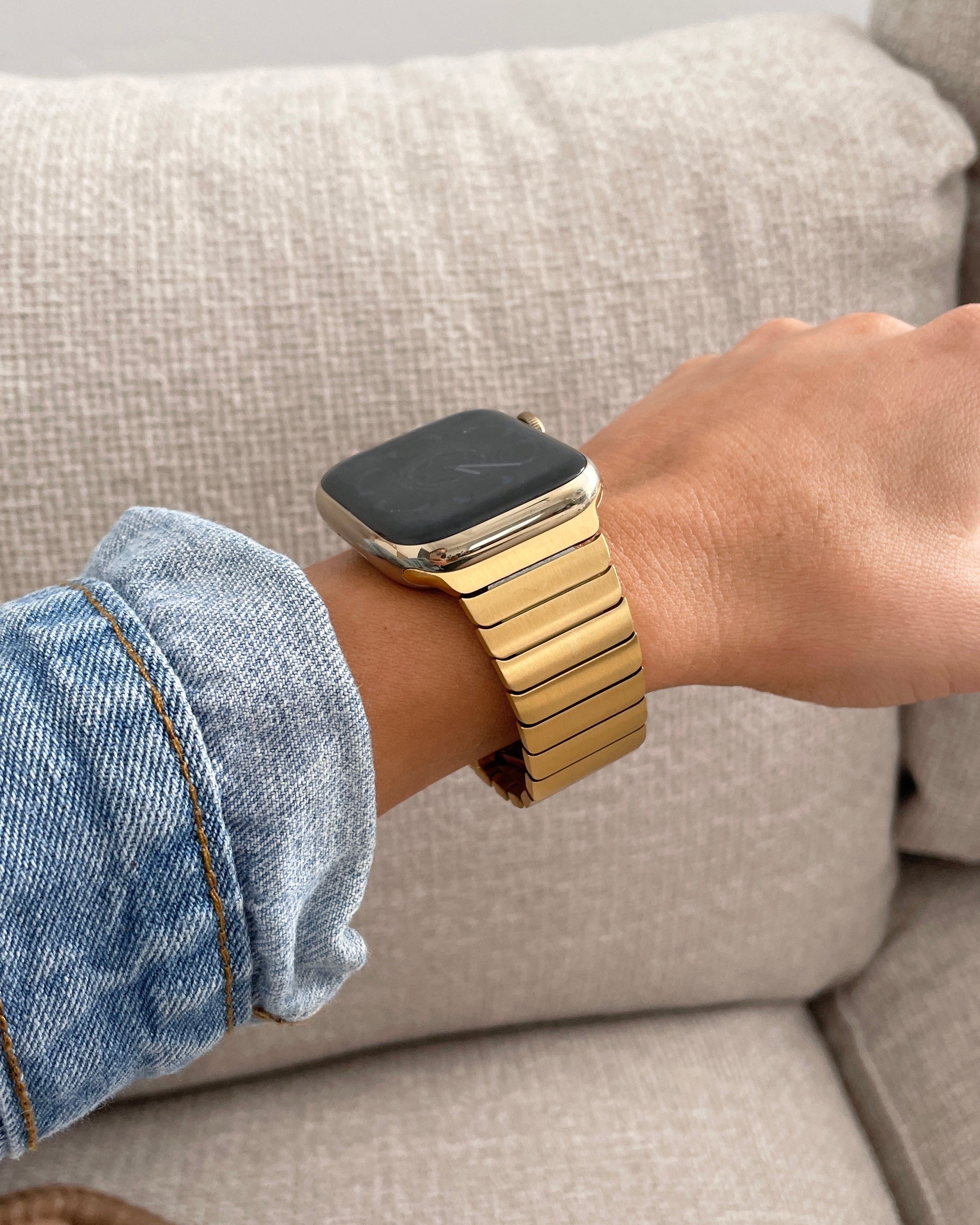 Person wearing a gold smartwatch on a neutral background