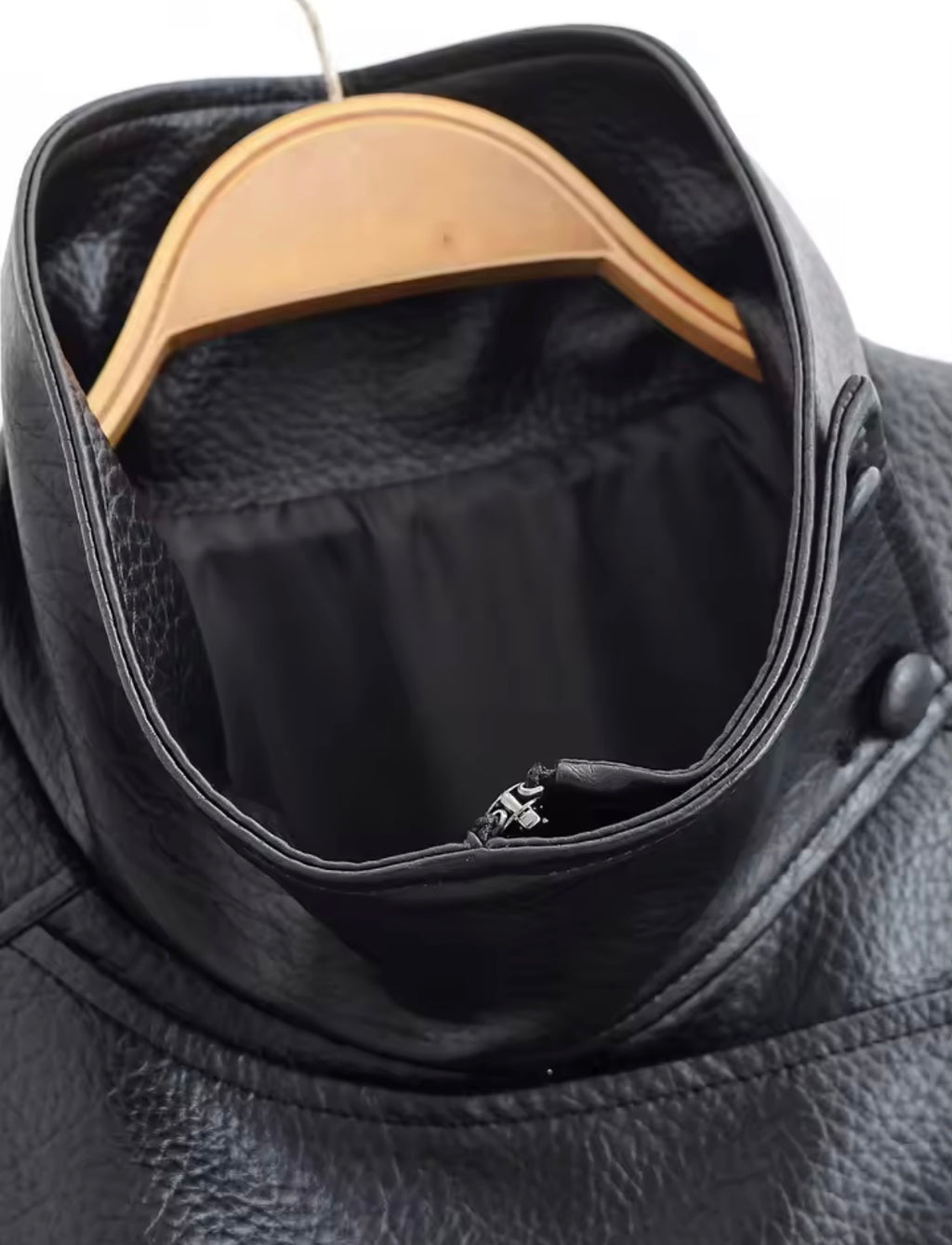 Black leather jacket with a wooden hanger inside, showing a brand logo.