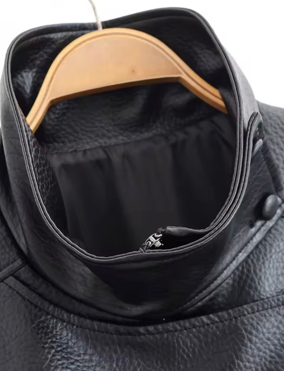 Black leather jacket with a wooden hanger inside, showing a brand logo.