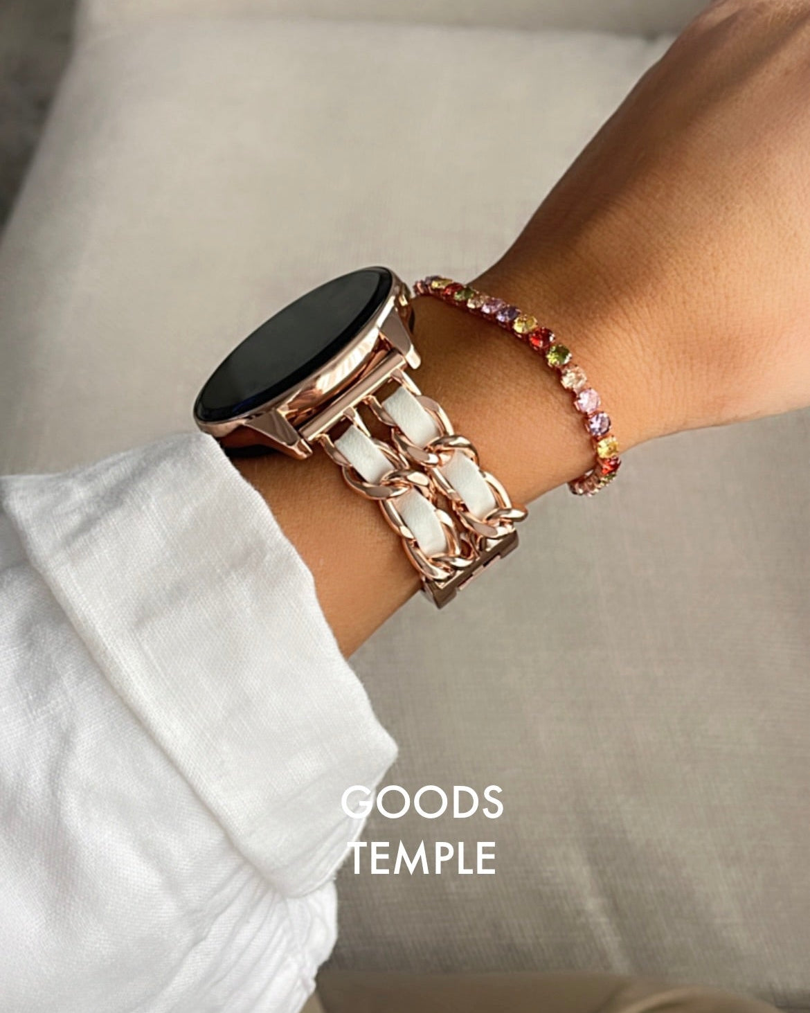 Person wearing a smartwatch and bracelet on a neutral background with 'GOODS TEMPLE' branding.