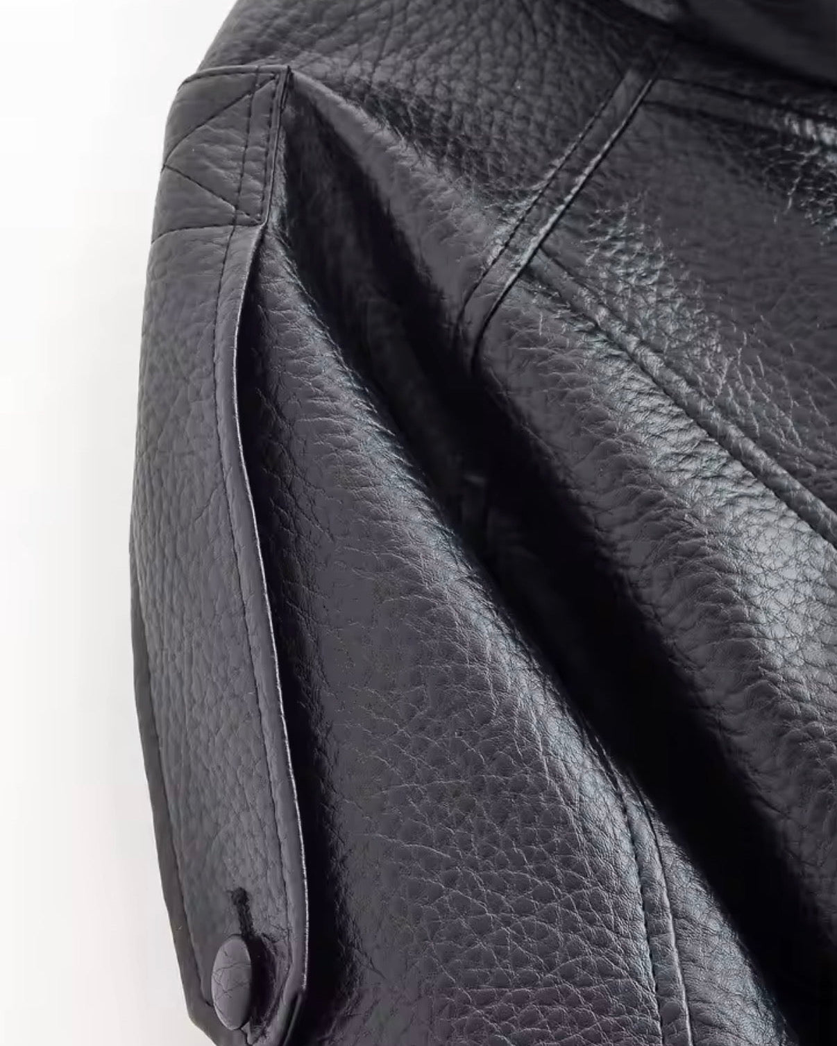 Close-up of a black leather jacket with a button on a white background