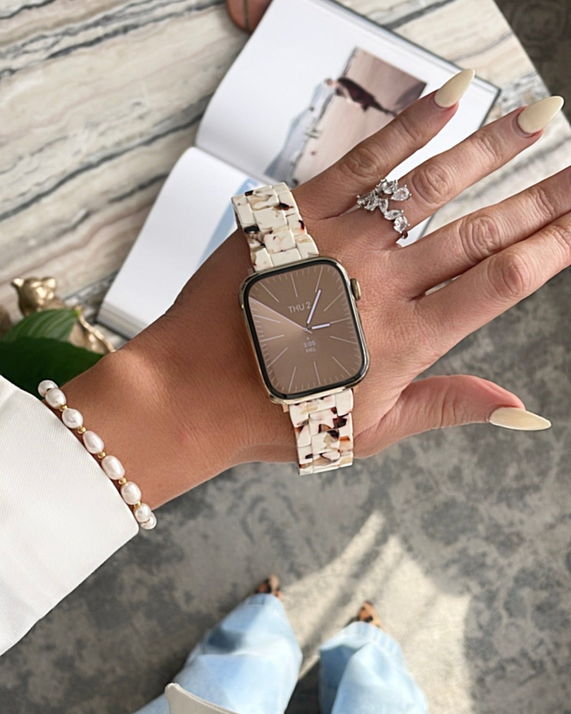 Hand wearing a smartwatch with a marble surface in the background