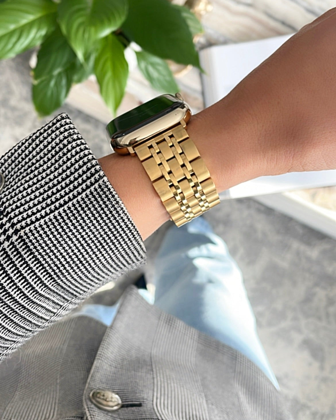 Person wearing a gold watch on marble coffee table 