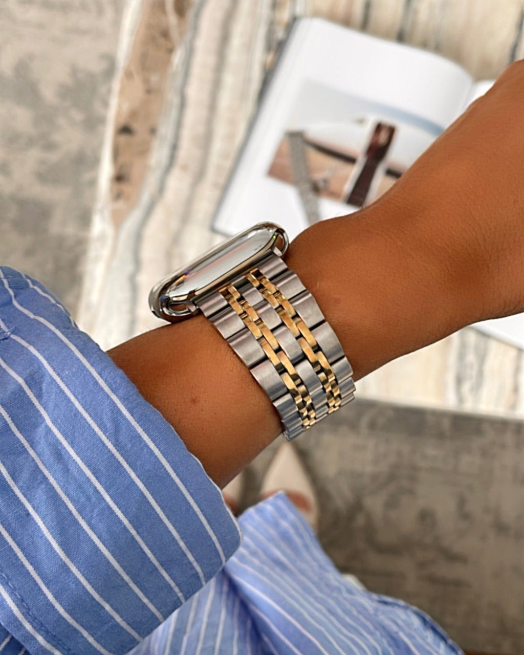 Close-up of a wrist wearing a silver and gold watch with a blurred background