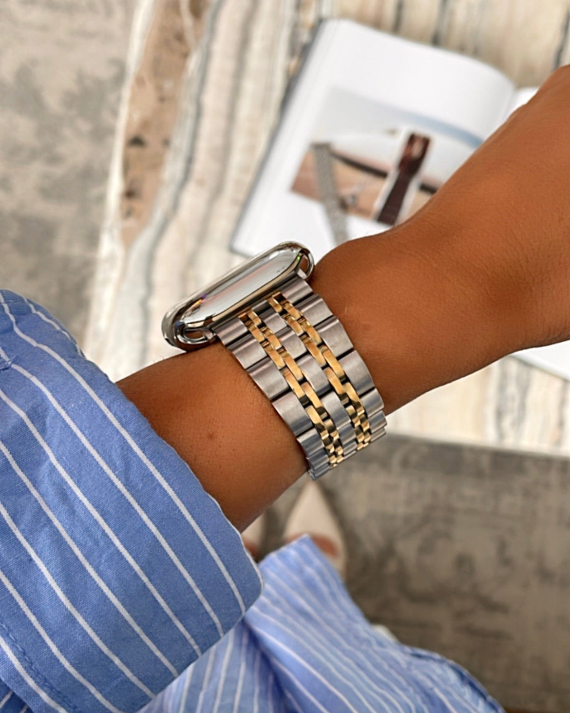 Close-up of a wrist wearing a silver and gold watch with a blurred background