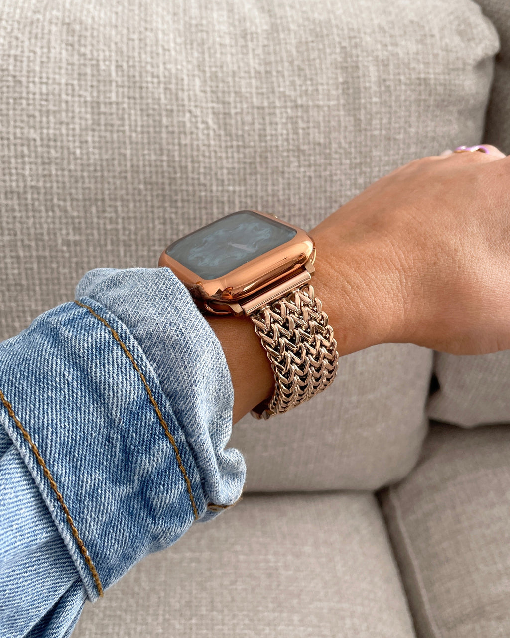 Person wearing a rose gold watch on a beige couch