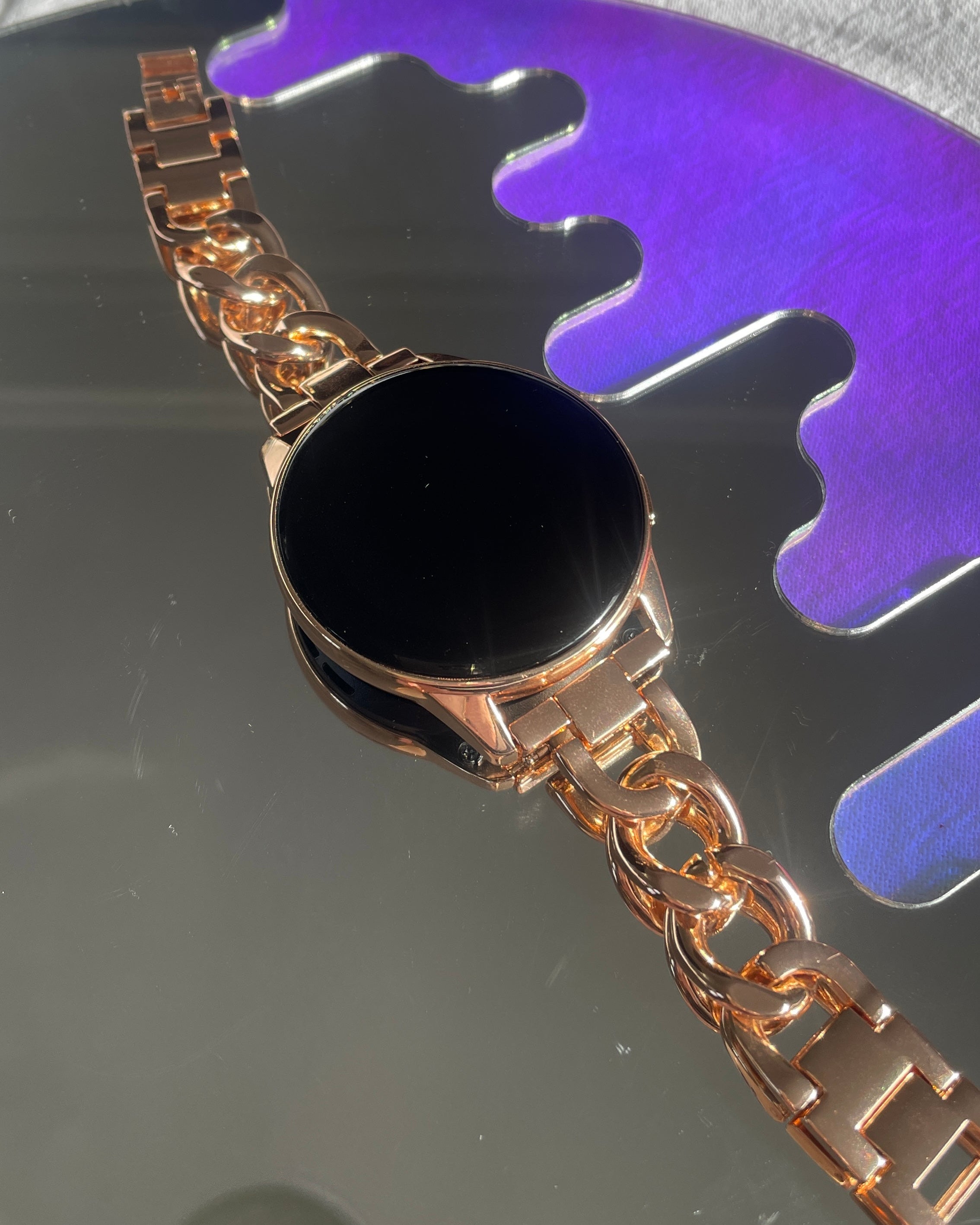 Rose Gold watch with a black face on a reflective surface