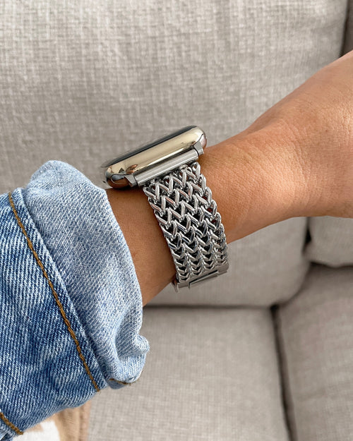 Person wearing a silver mesh watch on a beige couch